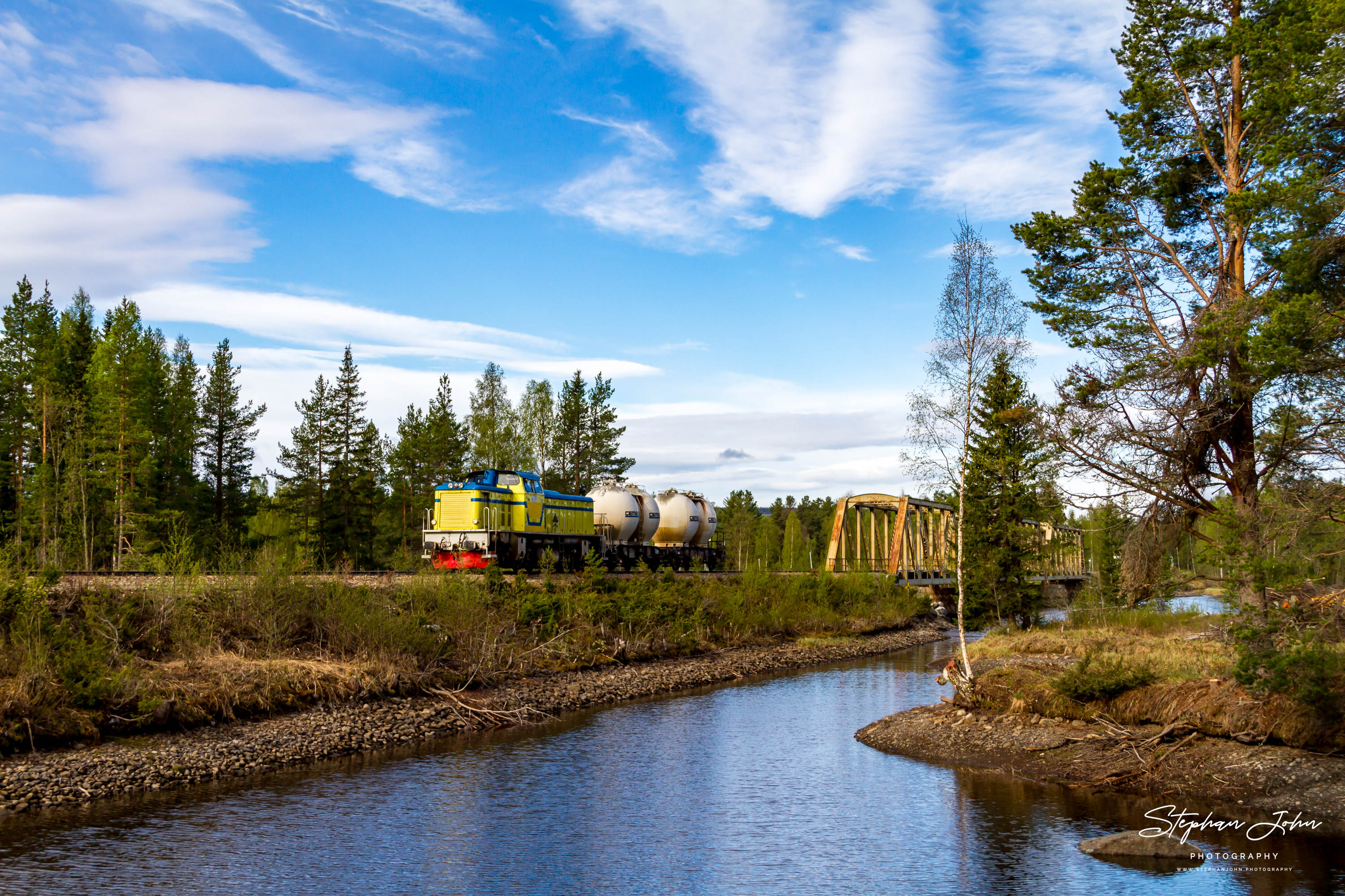 Ein kurzer Güterzug der Inlandsbanan in Schweden überquert den Fluß Hårkan bei Lit