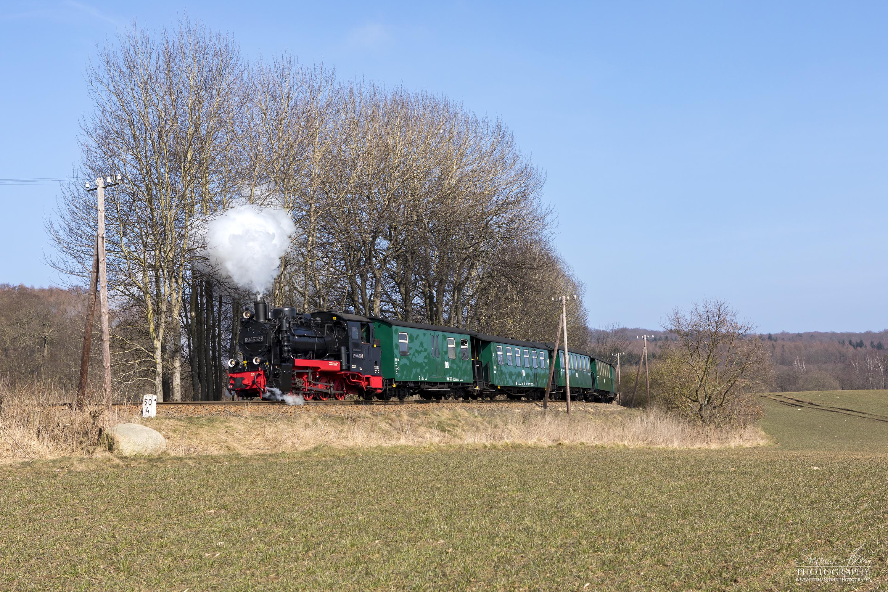Seit der Hauptuntersuchung im Januar 2018 hat die Rügen-Lok 99 4632-8 (Vulcan-Lok) wieder eine schwarze Reichsbahnlackierung. Hier zieht die Lok in der Granitz bei bestem Wetter einem Personenzug die Steigung nach Garftitz hoch.