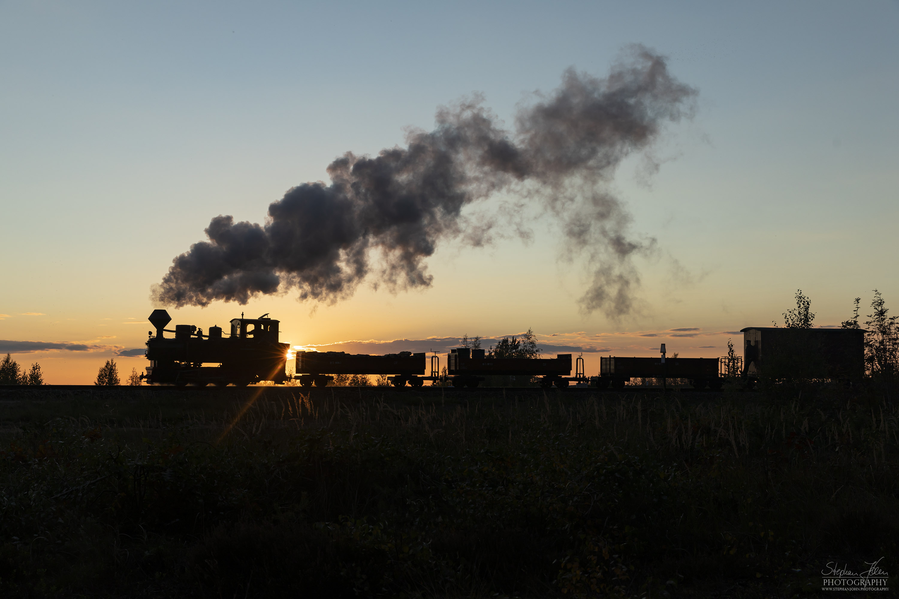 Lok 99 3312 zieht einen Güterzug im Sonnenuntergang zum Schweren Berg