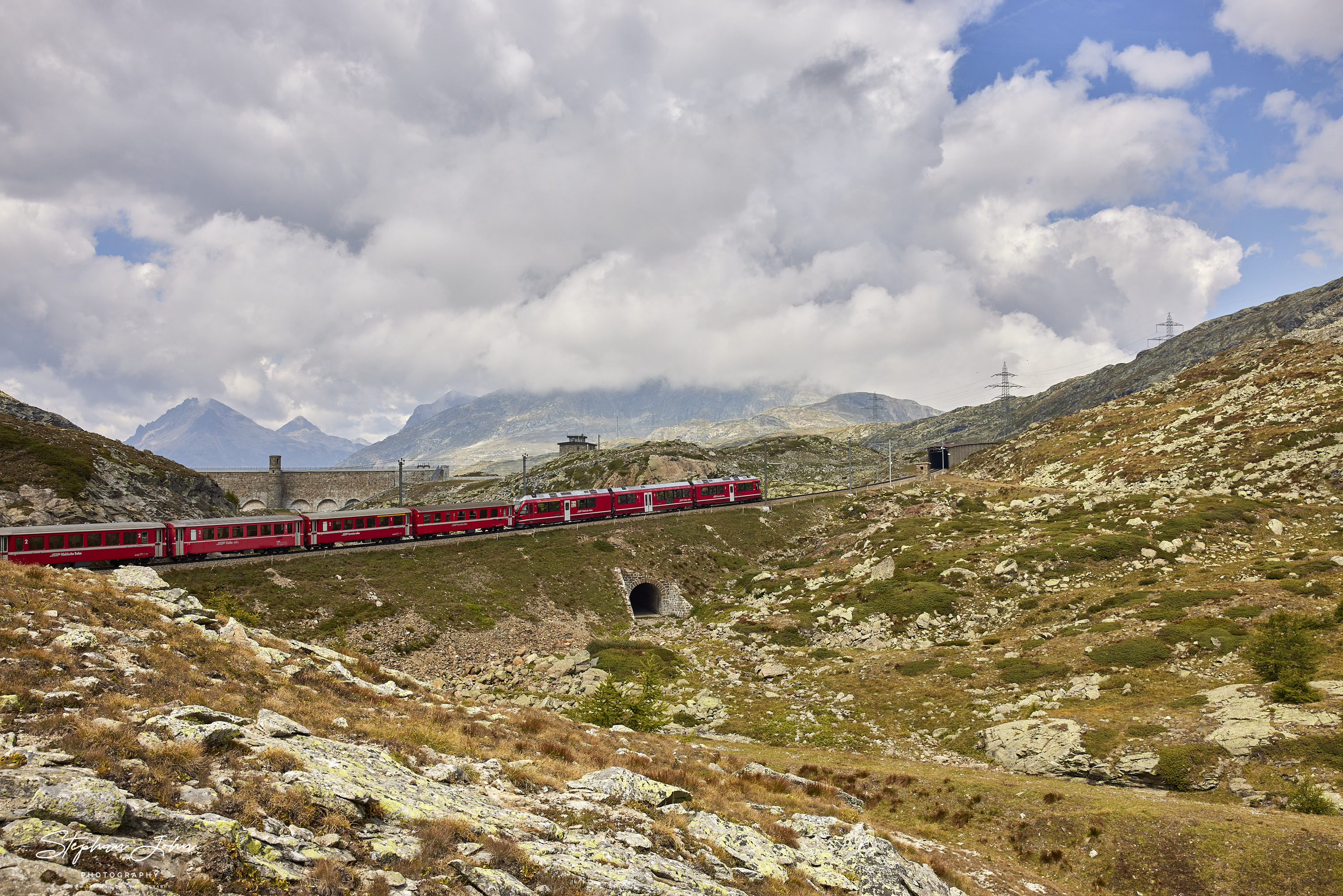 R 4648 von Tirano nach St. Moritz am Berninapass unterhalb der Staumauer des Lago Bianco. Im Vorderund ist noch die alte Trassierung der Strecke zu erkennen.