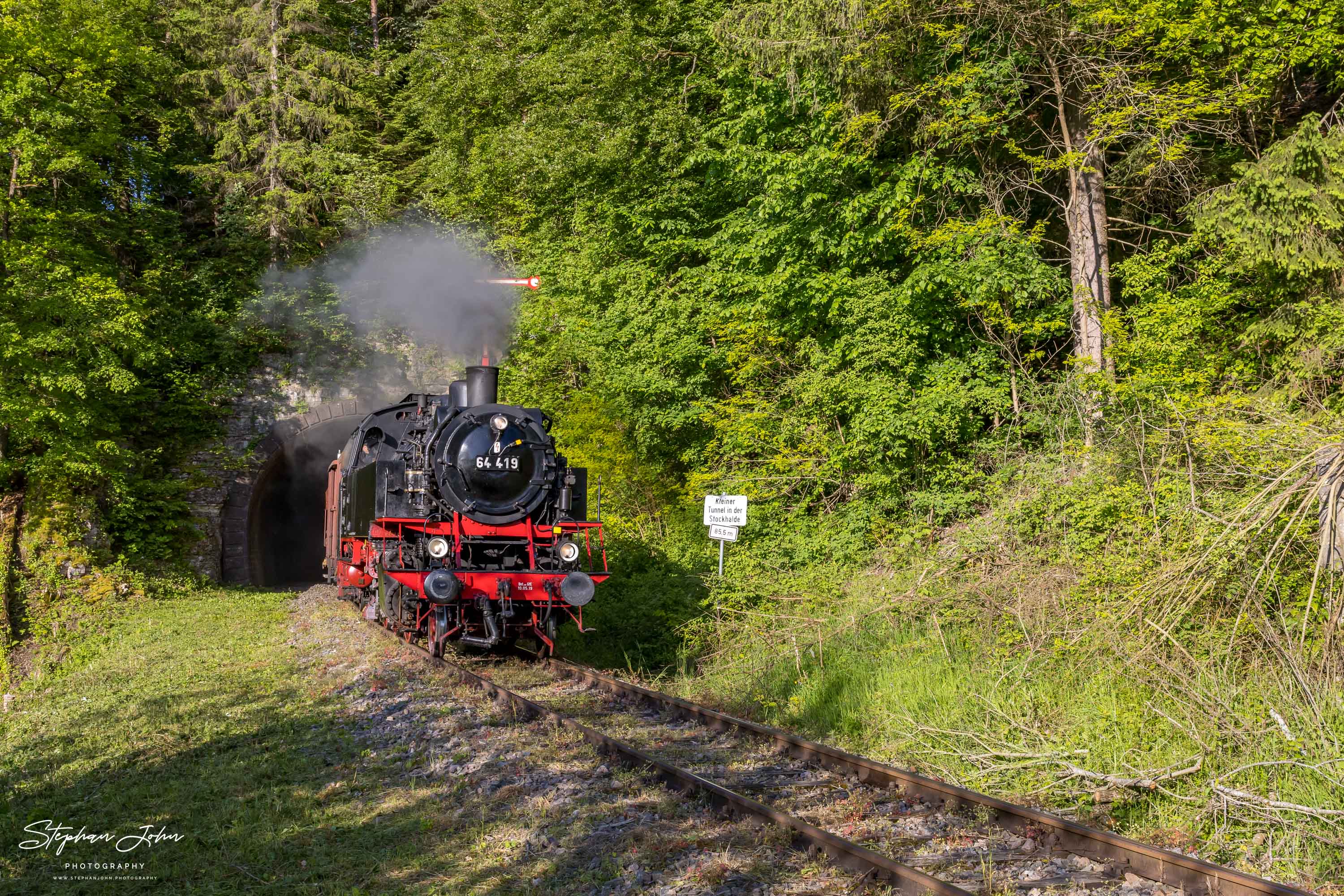 Lok 64 419 verlässt mit einem Güterzug den kleinen Stockhalde-Tunnel in Richtung Fützen