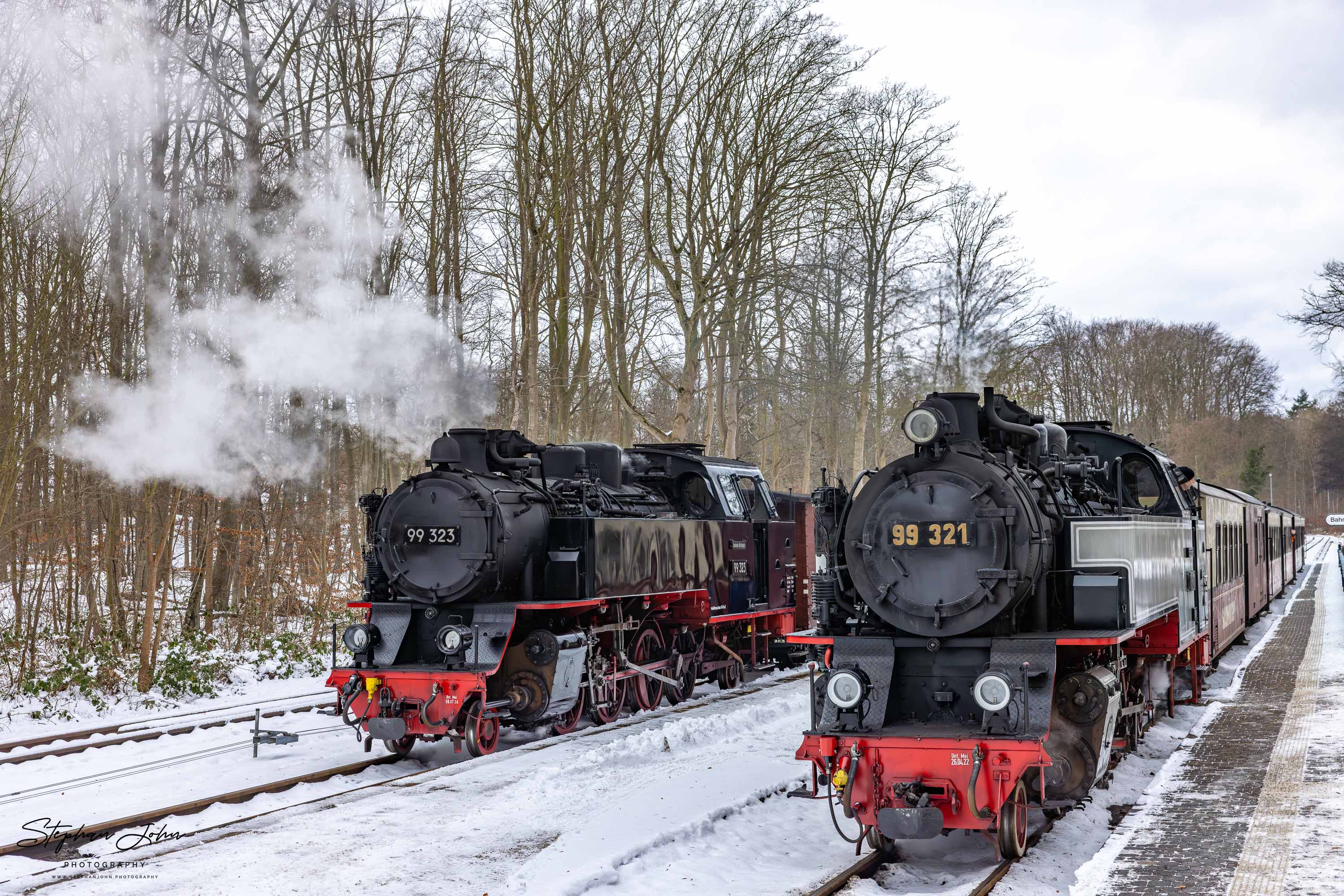 Lok 99 323 steht mit einem Güterzug im Bahnhof Heiligendamm und wird vom Personenzug mit Lok 99 321 überholt